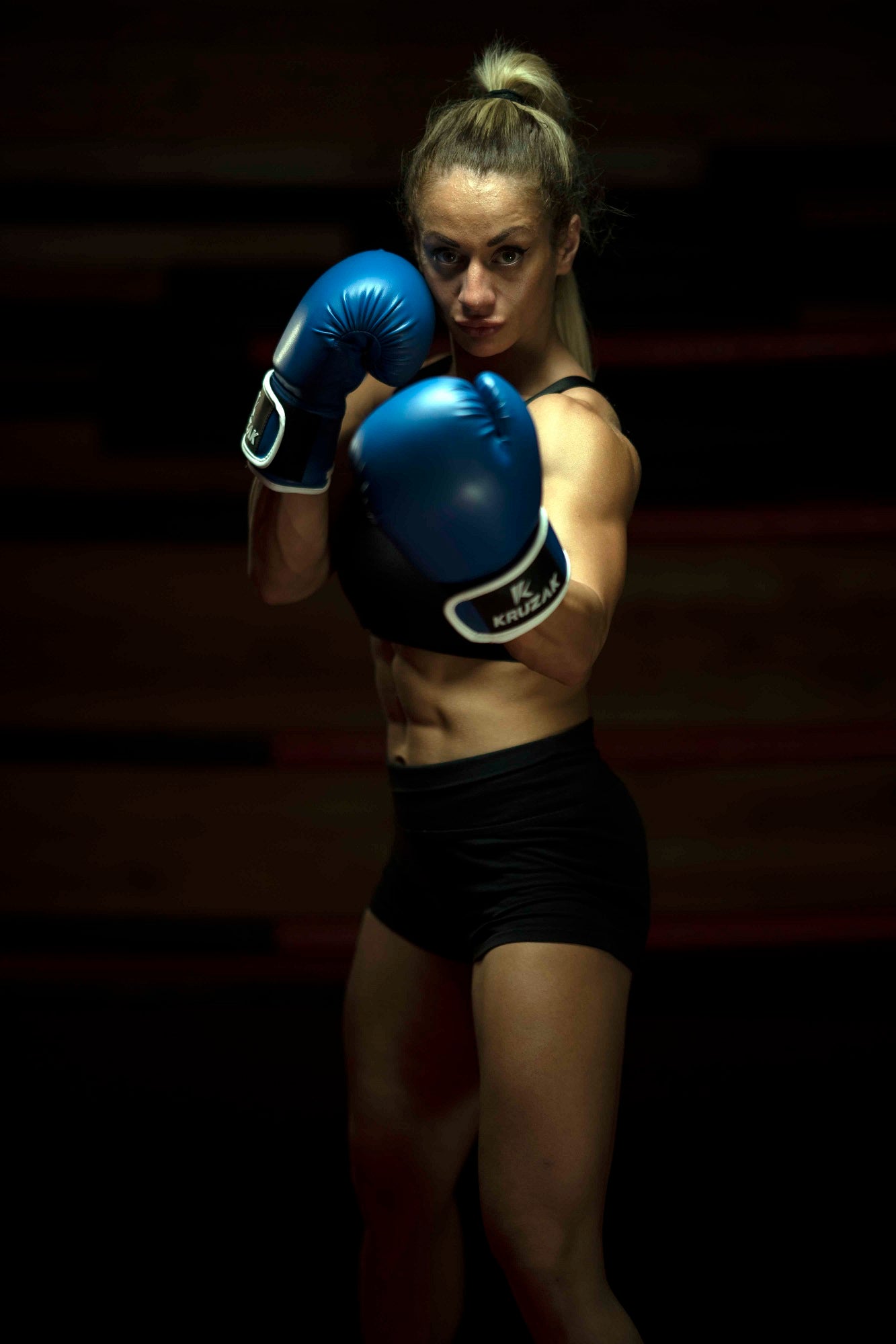 Woman in defense pose wearing Kruzak Blue boxing gloves