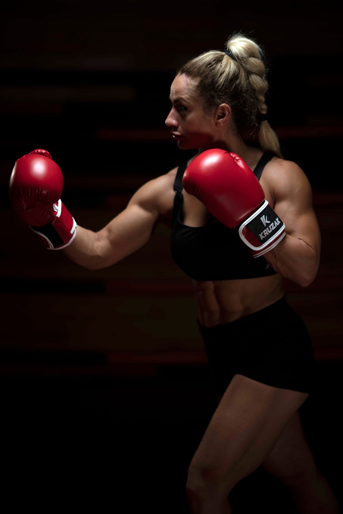 Woman in strike pose wearing Kruzak Red boxing gloves